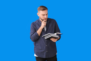 Thoughtful young man with books on color background