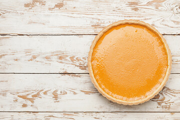 Tasty pumpkin pie on wooden background, top view