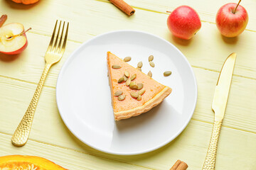 Plate with slice of tasty pumpkin pie on wooden background