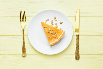 Plate with slice of tasty pumpkin pie on wooden background