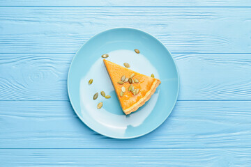 Plate with slice of tasty pumpkin pie on wooden background