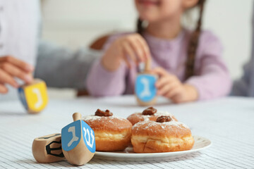 Plate with tasty donuts for Hannukah and dreidels on table