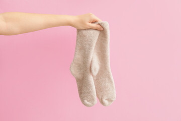 Hand with warm socks on color background