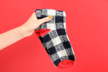 Hand with warm socks on color background