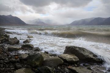 Picturesque seascape. Surf and waves during a storm. View from the coast to the sea bay and mountains. The nature of the Arctic. Egvekinot Bay, Kresta Gulf, Bering Sea, Chukotka, Far East of Russia.