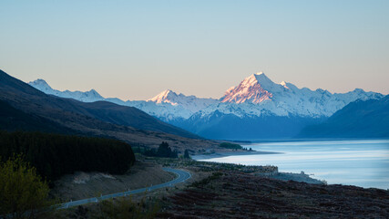 Fototapeta na wymiar Mount Cook road and snow-capped mountains in the background along the shoreline of Lake Pukaki, South Island, New Zealand