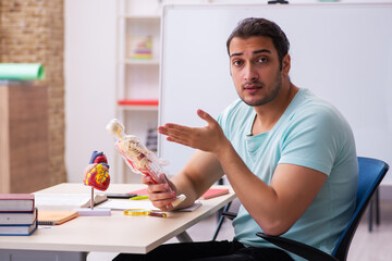 Young male student medic studying human anatomy at home