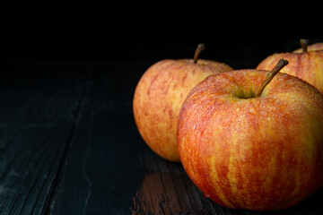 Wet red apples under on dark wooden table