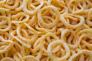 Background food. Round chips with paprika in the form of rings. Studio light. Party snacks. a fresh and spicy snack of potato chips. A bunch of crunchy onion rings.