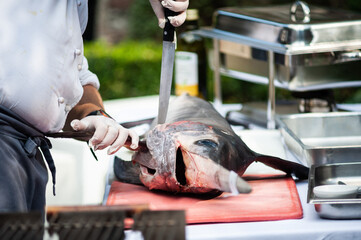 cook cuts whole swordfish - freshly caught in the kitchen ready to be prepared swordfish