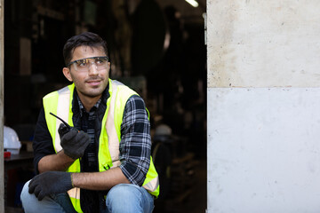 smiling handsome engineer man or factory worker using walkie-talkie and feeling happy