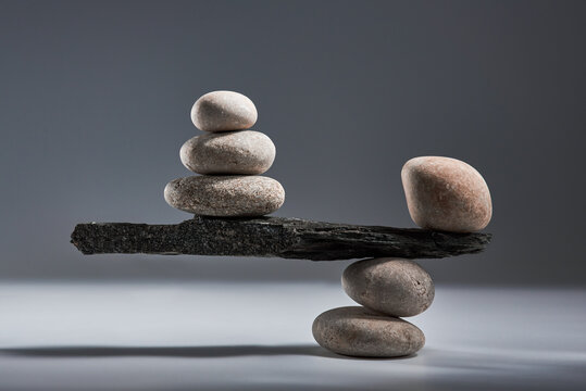 Balancing pyramid of sea pebbles on a gray background, the concept of harmony and balance, heavy and light. Stones in the form of scales with balancing stones.