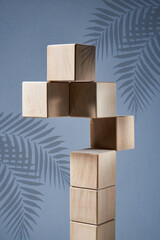 Balancing pyramid of wooden square blocks on a blue background, the concept of harmony and balance, heavy and light.