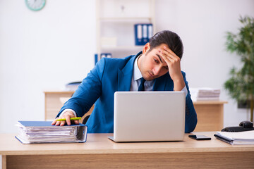 Young businessman employee unhappy with excessive work in the of