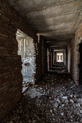 Fototapeta na wymiar A long dark corridor in a dilapidated modern concrete building with broken brick walls