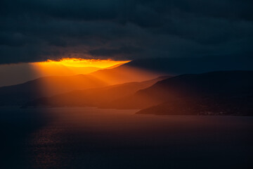 The last rays through the dark clouds at sunset illuminate the southern coast of Crimea