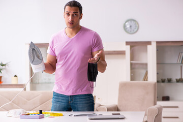 Young male tailor ironing mask during pandemic