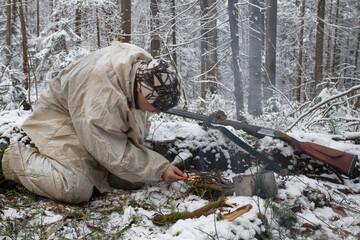 a hunter makes a fire in the winter forest