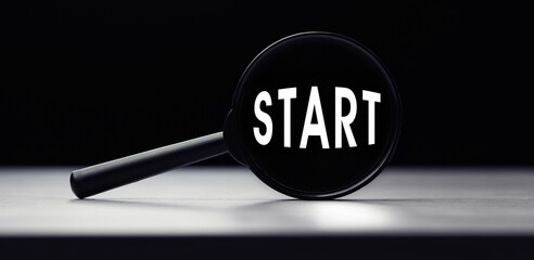 Magnifying glass with the word START on table