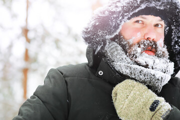 Outdoor portrait of handsome man in coat and scurf. Bearded man in the winter woods.