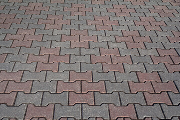 Red-gray paving stones on the sidewalk laid out in a checkerboard pattern. The concept of paving slabs and paving stones. Concrete paving blocks. Rough background, texture.