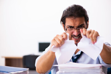 Young male employee unhappy with excessive work in the office