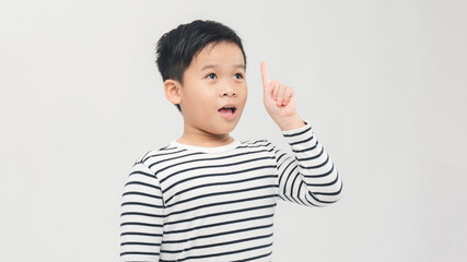 Portrait of smart little boy with curly hair pointing finger up and looking inspired by genius thought, having clever solution in mind.