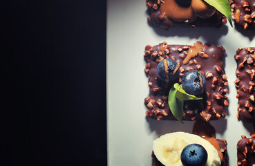 Chocolate dessert with nuts and fresh berries. Sweet snack for coffee biscuit in glaze and nut crumbs with fruit.
