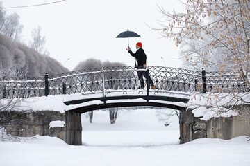 Fototapeta premium Winter walk with an umbrella.Man in a coat with an umbrella, walk against the backdrop of the winter landscape, winter view