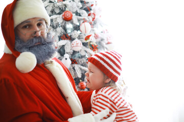 Obraz premium Santa Claus sitting with little cute elves over Christmas background. Time of miracles. Gifts from Santa Claus.