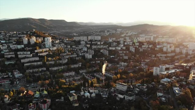Aerial view of houses with mountain views. Residential area at dawn with a steaming pipe. Sochi city.
