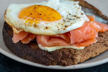 Fresh salmon, egg sandwich, close up. Salted salmon, fried egg, butter and dark bread