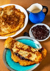 2 plate with fried potato pancake, blue pitcher, plum jam on table.