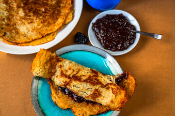 2 plate with fried potato pancake, plum jam on plate with spoon on table