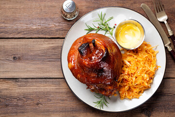 Roasted pork knuckle with braised boiled cabbage and mustard on wooden background. Flat lay.