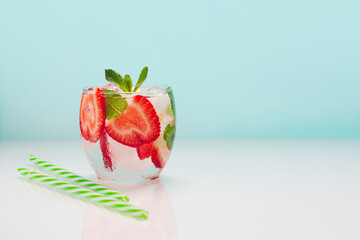 Fresh summer drink with strawberries and mint on a blue background.