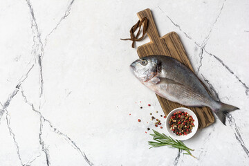 Fresh fish dorada or gilt-head bream on cutting board with spices