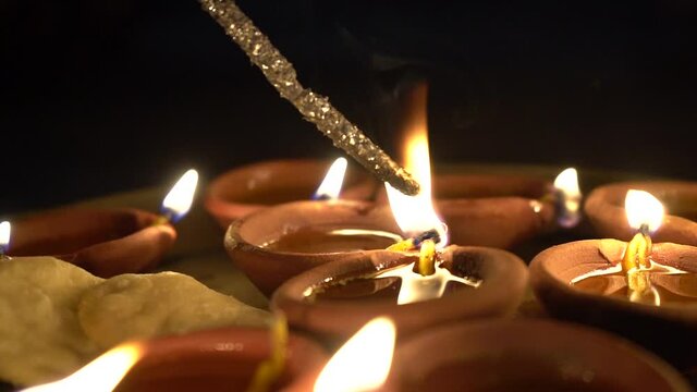 slow motion side shot of Phuljhadi being lit from a diya oil lamp placed in a plate with it lighting up and sparks flying out shot on the indian festival of Diwali