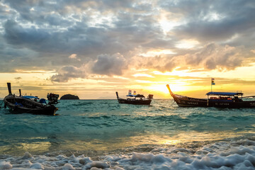 Obraz premium Sea beach sunset sea wave with boat against colorful sky cloud