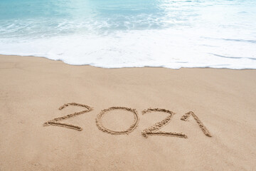 Hello 2021 sign on the sandy beach with soft wave of white foam. Welcoming 2021 with new resolutions, dreams concept.