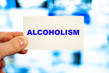 Doctor's diagnosis ALCOHOLISM on a white sheet against the background of liver pictures in the hospital.