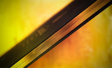 Golden edge of a black book, diagonal, toned in fortuna gold color, close up, selective focus