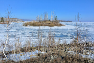  Winter landscape. An island on a frozen lake on a clear Sunny day.