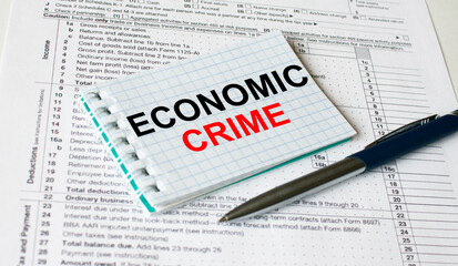 Notepad with text Economic Crime lying on financial tables with a pen