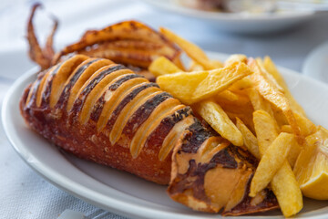 Grilled fresh squid on white plate with lemon and chips.