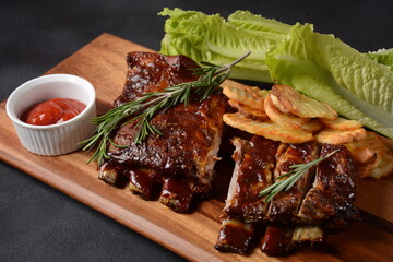 Closeup of pork ribs grilled with BBQ sauce and caramelized in honey. Tasty snack to beer on a wooden Board. Grilled pork ribs with spices on a stone background
