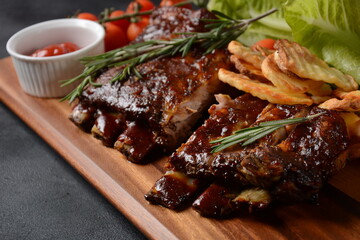 Closeup of pork ribs grilled with BBQ sauce and caramelized in honey. Tasty snack to beer on a wooden Board. Grilled pork ribs with spices on a stone background