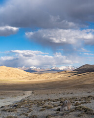 Fototapeta na wymiar Spectacular view on snow-capped mountains from high-altitude Khargush pass in Gorno-Badakshan, the Pamir region of Tajikistan with dirt road