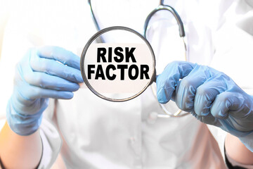 The doctor's blue - gloved hands show the word RISK FACTOR - . a gloved hand on a white background. Medical concept. the medicine