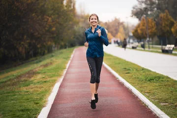Poster Beautiful adult woman is jogging outdoor on cloudy day in autumn. © djoronimo